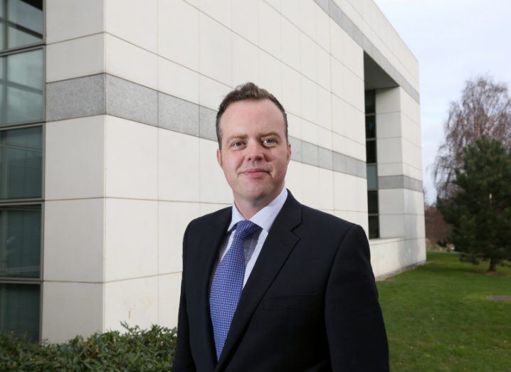 OncoMark co-founder Prof William Gallagher standing in front of a building in UCD. Trees in the background.