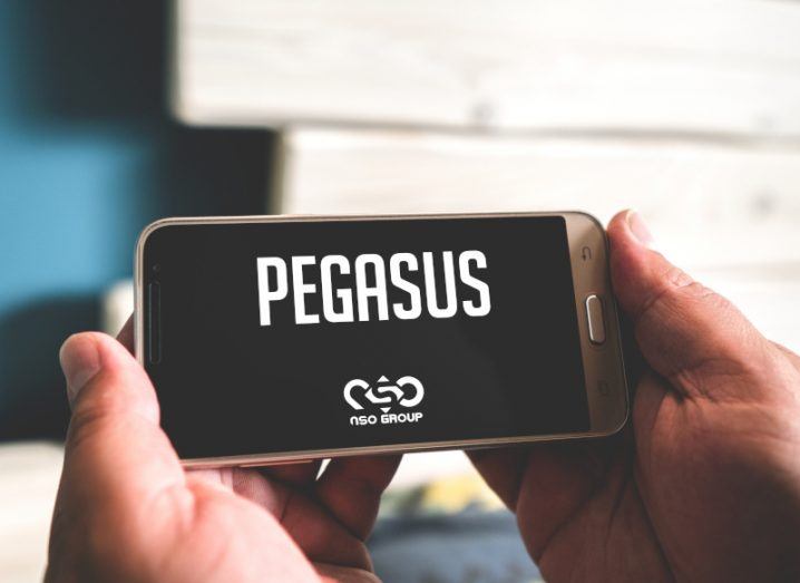 Hands holding a smartphone with the Pegasus and NSO logos on the screen.