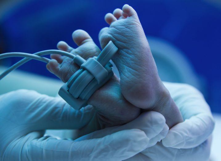 Image of baby's feet in the hands of a doctor wearing gloves.