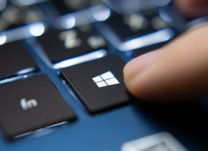 Finger pressing the Windows key on a laptop keyboard.