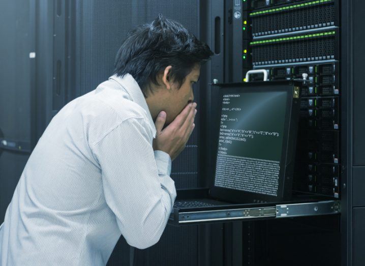 Man looking concerned while reading a monitor connected to a supercomputer.