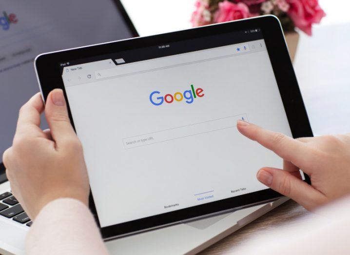 Person holding a tablet computer with the Google search engine on the screen.