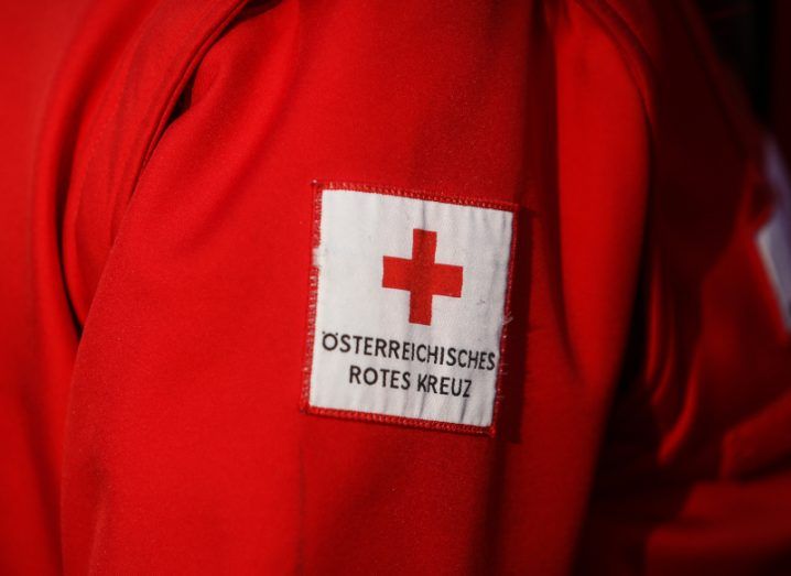Logo of the Austrian Red Cross organisation on the arm of a red jacket.
