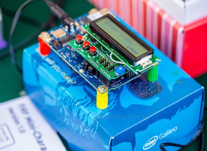 A Galileo computer board with an LCD display and other computing boards connected to it, pictured on top of a branded Intel package.