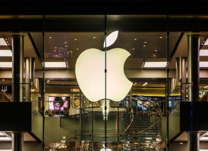 The Apple logo on the front of a building with lights visible behind it.