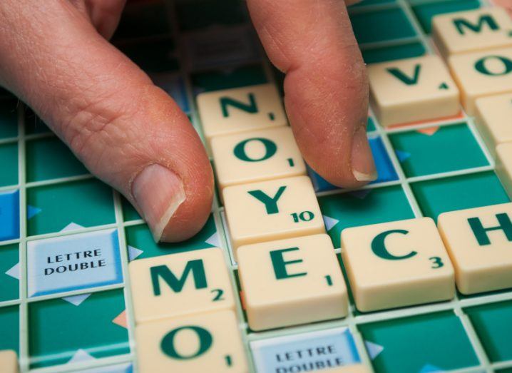 Person playing scrabble, putting down letter pieces on a board.