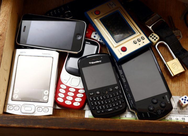 A BlackBerry and several other smartphones and older tech devices in a drawer.