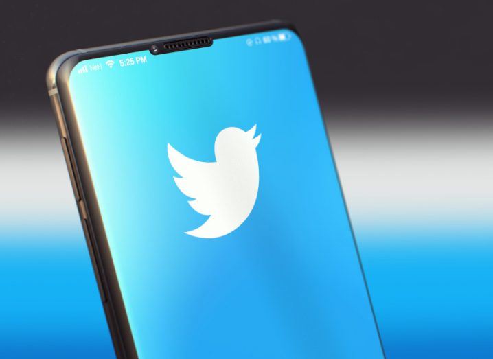 Smartphone displaying Twitter logo against a blue background.