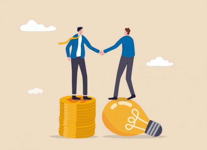 Cartoon business person standing on a pile of gold coins shaking hands with another business person standing on a giant gold lightbulb.