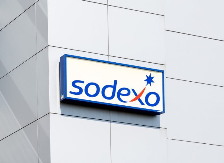 Sodexo logo on a square panel in the front of a grey building.