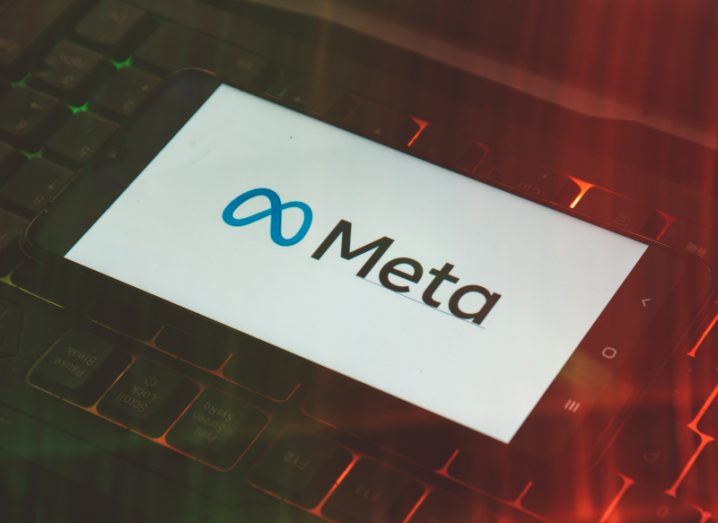 Smartphone displaying Meta logo lying on top of a backlit keyboard.
