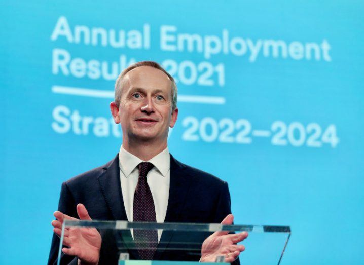Leo Clancy stands on a podium in front of a screen that says 'Annual employment results' and 'Strategy 2022-2024'.