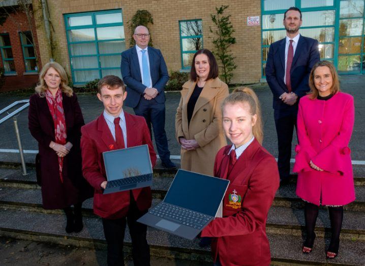 seven people celebrating Microsoft Ireland's education initiative in Northern Ireland. Two are holding laptops.