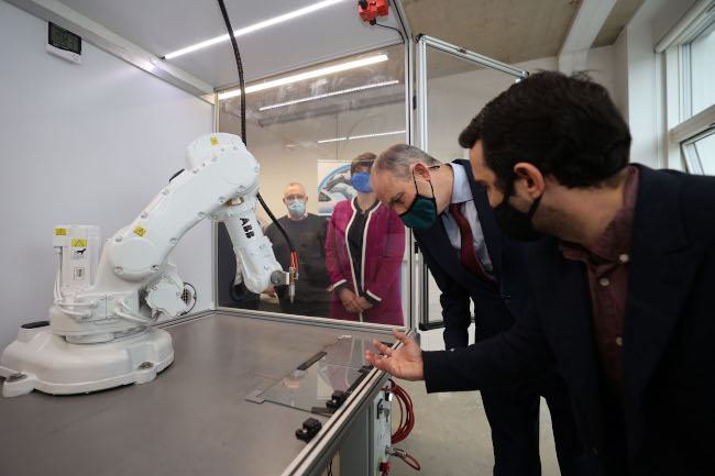 Micheál Martin peers closely at a large white robotic arm as Nick Barry explains the technology to him.