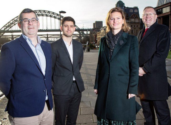 Three men and a woman at Version 1 tech hub announcement in Newcastle standing in front of the city's iconic bridge.