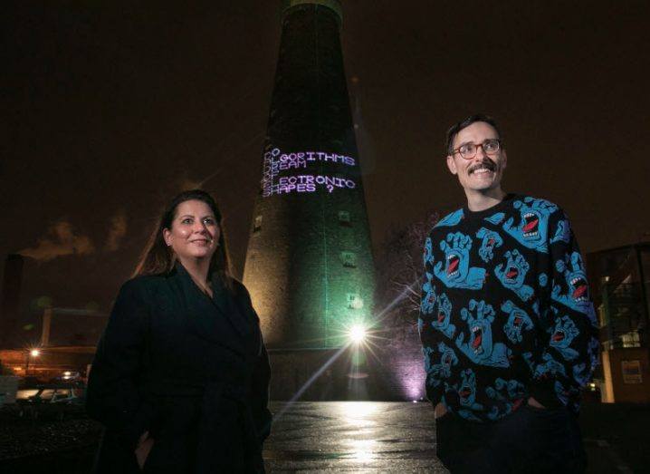 Caroline Viguier of the Digital Hub and artist Robin Price standing in front of the St Patrick's Tower in Dublin.