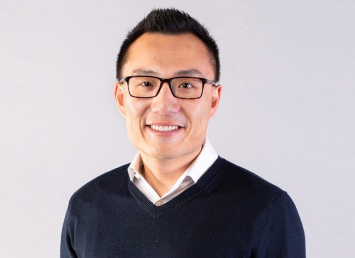 A headshot of Tony Xu wearing a black sweater and glasses.