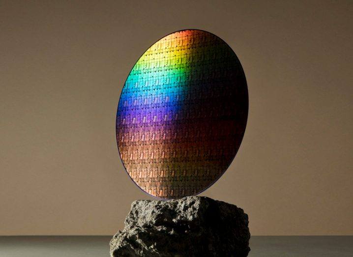 A multicoloured disc reflecting light is kept on a rock.
