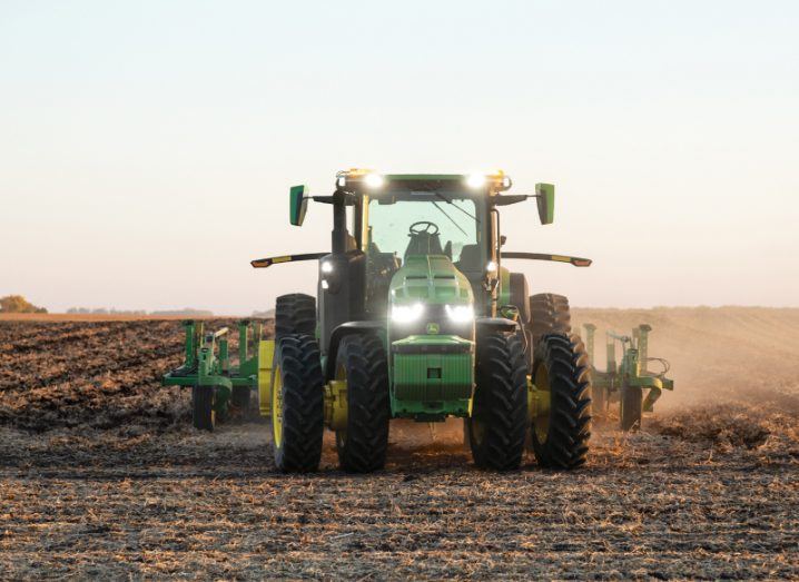 An autonomous John Deere tracking is driving through a field, with no person in the cab.