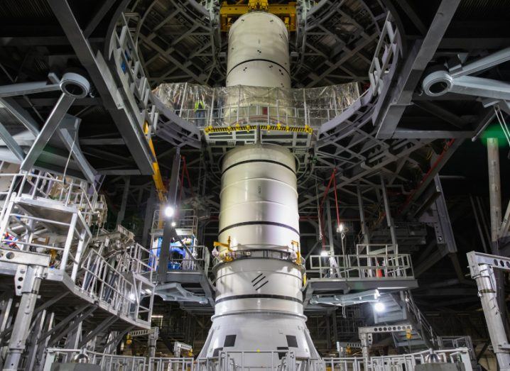 A rocket component being assembled in a large NASA building.
