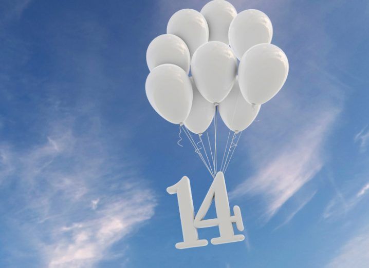 The number 14 hanging from white gas balloons in the sky.