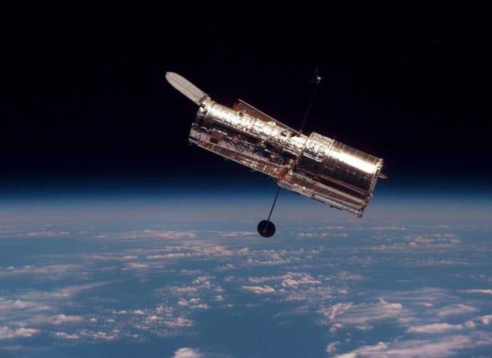 The Hubble telescope in orbit above Earth, looking out toward space.