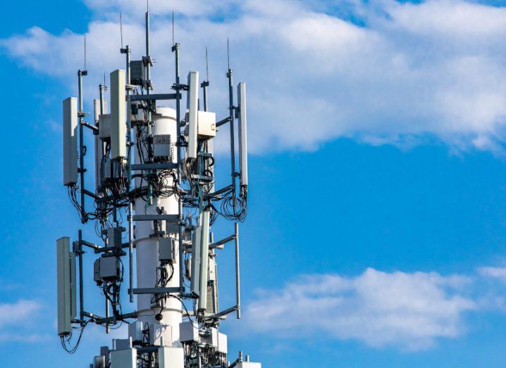 A 5G telecoms tower against a bright blue sky.