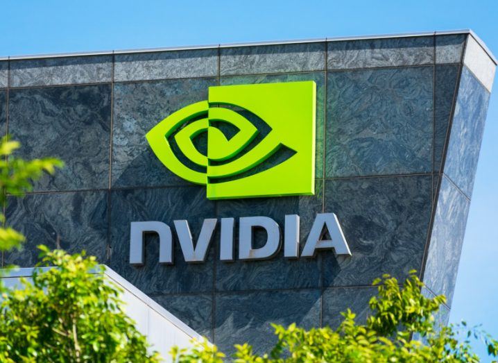 Nvidia logo and name on the front of a building with some trees in the foreground and a blue sky above it.