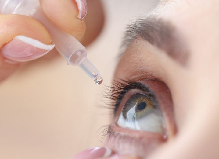 A person putting drops into their eye using a dropper.