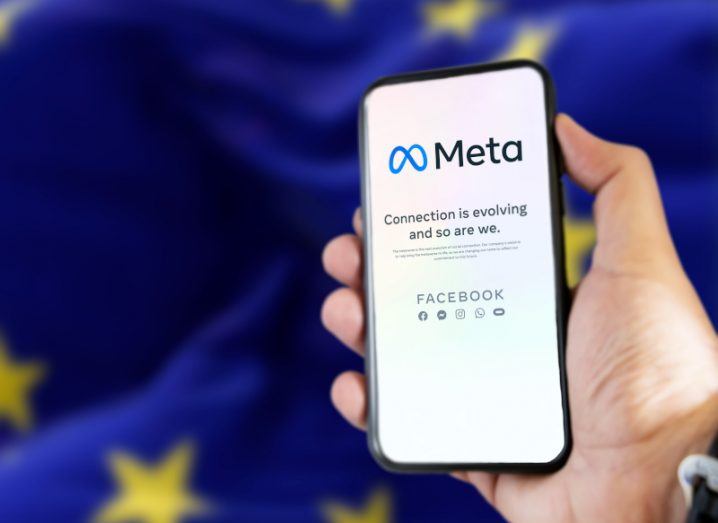 Meta logo on a mobile phone screen in front of the EU flag.