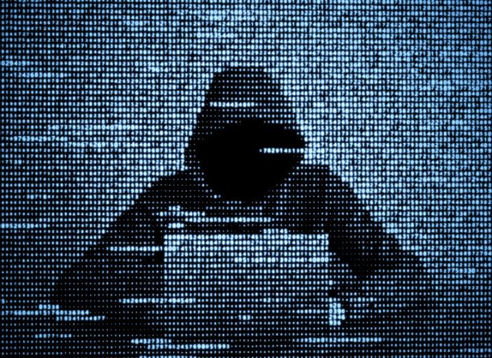 Illustration of a hacker wearing a black hoodie and seated in front of a laptop.