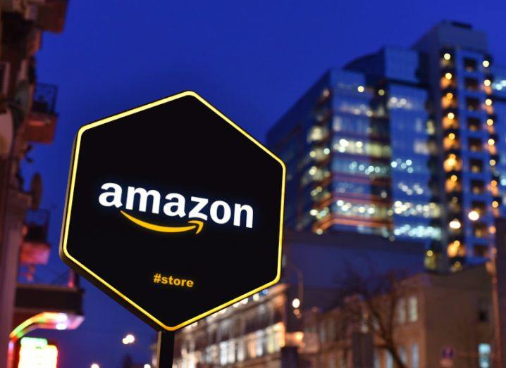 Amazon logo on a sign in the streets with blurred tall buildings in the background.