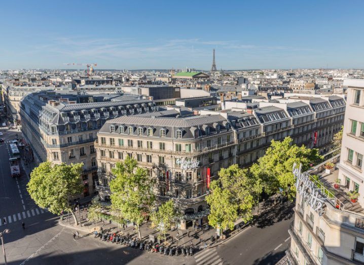 The Paris city skyline with a big Galeries Lafayette building in centre, surrounded by trees and streets.