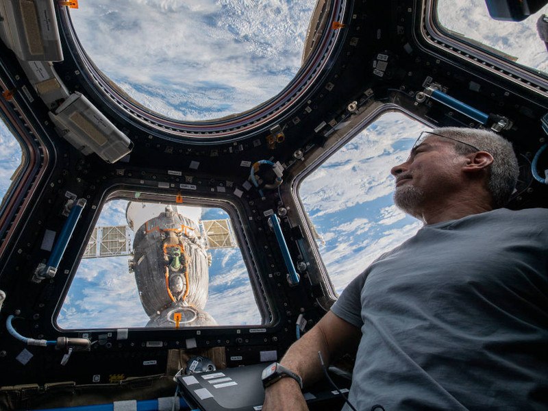 A man peers at the Earth from the windows of the ISS.