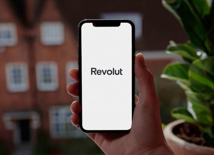 Smartphone with the Revolut logo displayed on screen held in a person's hand.