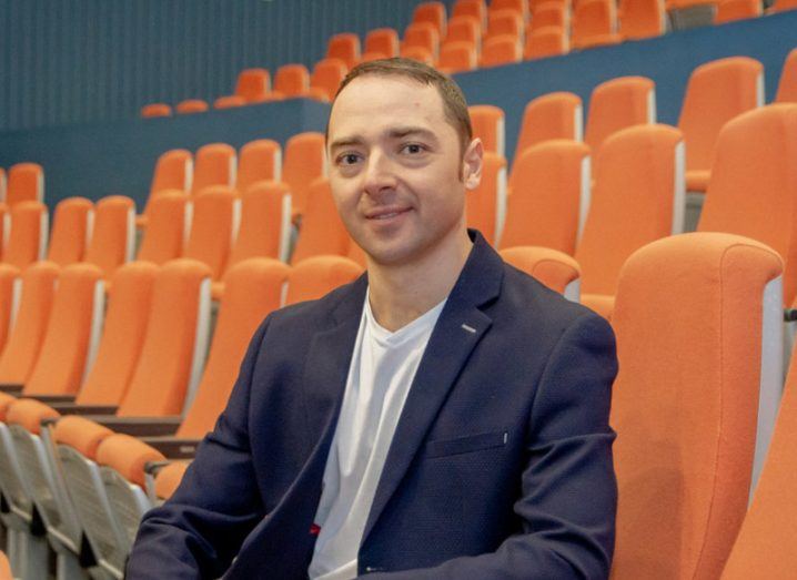 Translit CEO Alex Chernenko sitting with orange chairs lined in the background.