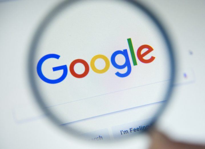 Google logo on a screen being looked at through a magnifying glass.