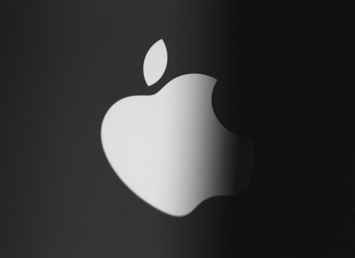 Apple logo on the back of an iPhone, with a portion of the logo shrouded in darkness.