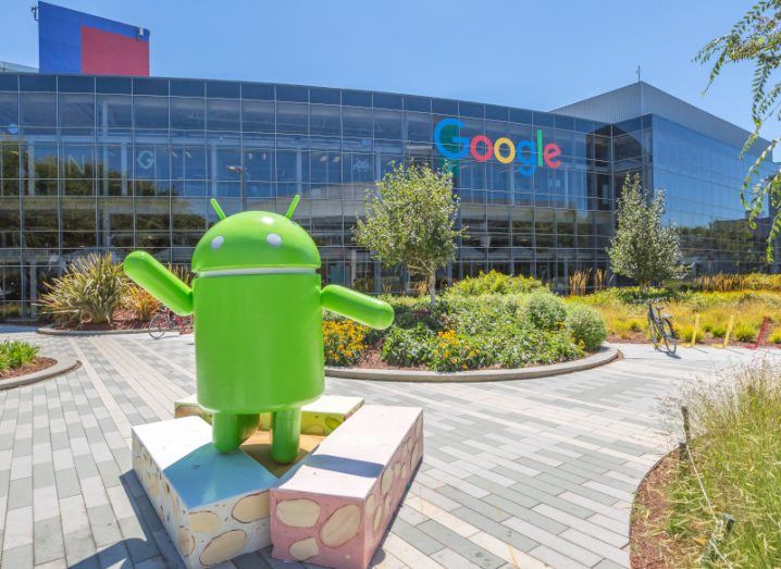 Google building with the company's logo on it, with the Android logo character standing in a courtyard in front.