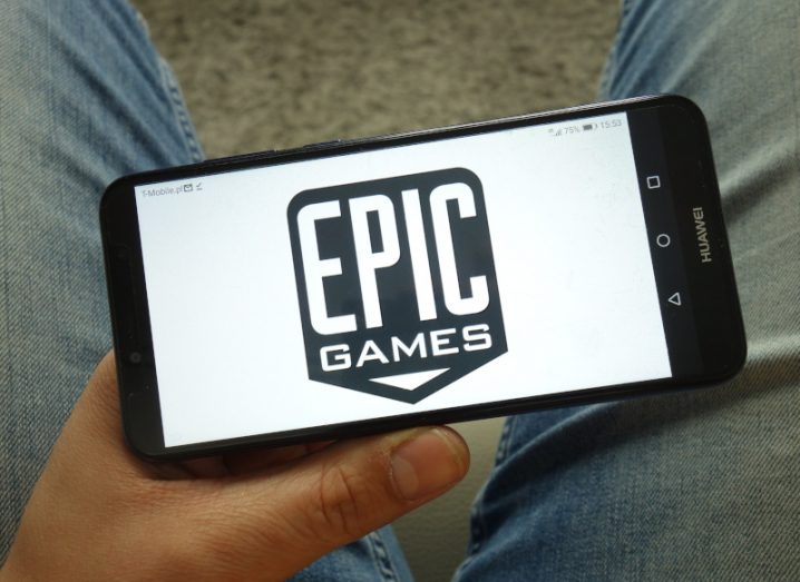 Epic Games logo with a white background on a mobile phone being held in a person's hand.
