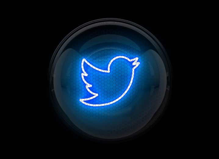 Twitter logo with blue neon lighting in a dark background.