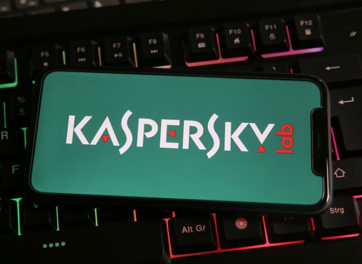 Kaspersky Labs logo on a mobile phone with a green background, resting on a computer keyboard.