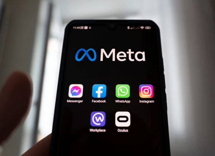 A smartphone screen displays the Meta logo above the company’s suite of apps: Facebook, WhatsApp, Instagram, Messenger, Workplace and Oculus.
