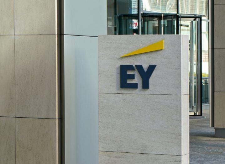 The EY logo on a large stone sign outside an office building.