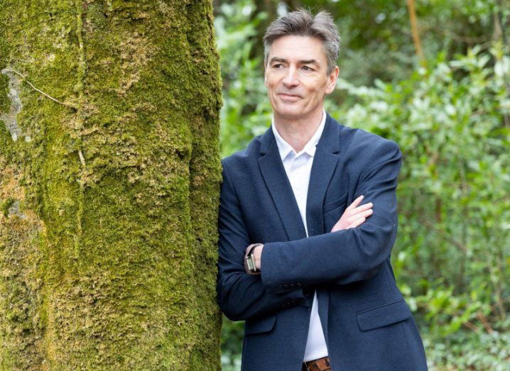 Donal Sullivan, the new CEO of climate action AI company Future Planet leaning against a mossy green tree.