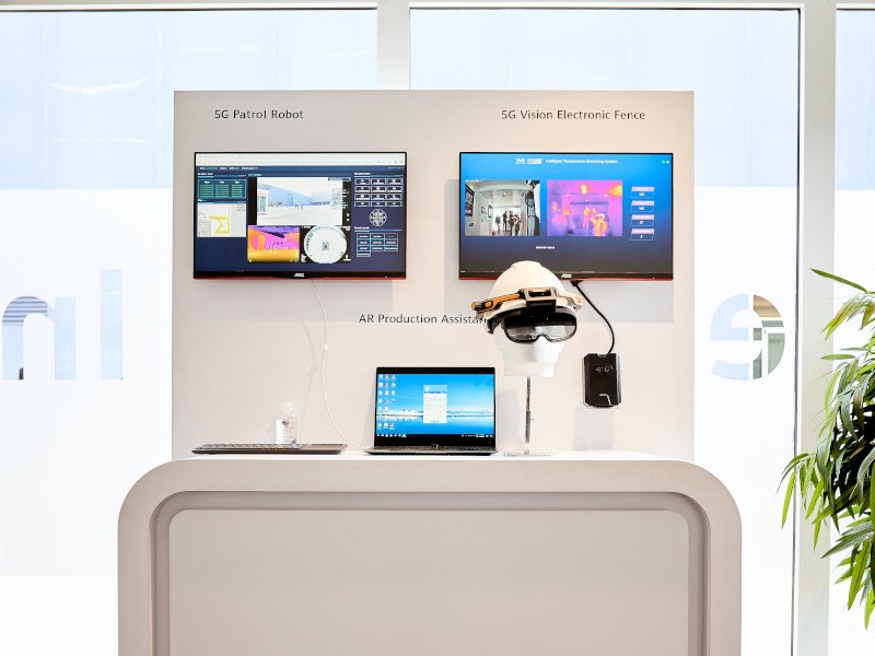 A Huawei AR headset in front of computer screens and a laptop.