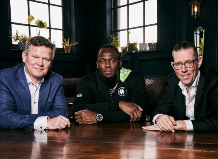 David Cronin, Usain Bolt and Steve Daly sit around a table in a dark room.