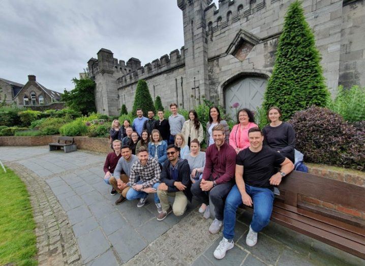 A group of people standing and seated in front of a castle.