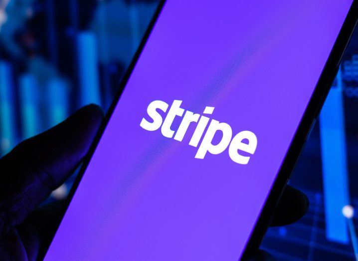 Stripe logo on a smartphone screen held in a person's hands.