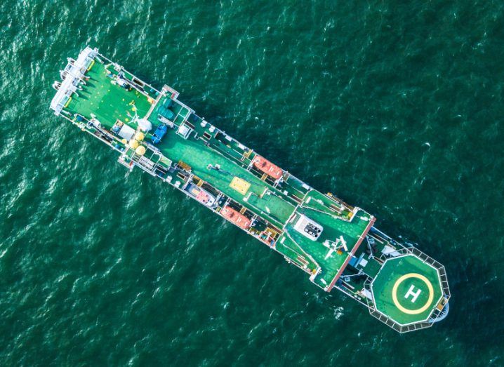 Aerial view of a cable laying ship over green waters.